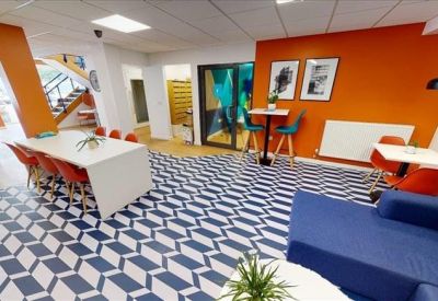 Bright communal lounge with an orange feature wall, blue sofa, and geometric patterned flooring.