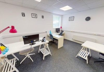 Bright private office suite with white desks, grey carpeting, and a red desk lamp.
