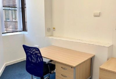 Private office featuring a wooden desk, blue mesh chair, and natural light from a window.