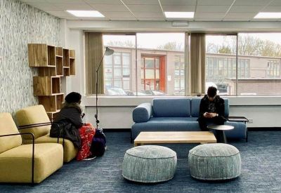 Spacious lounge at Kingspark Centre, 152-178 Kingston Road, with a blue sofa, yellow chairs, and modern shelving.