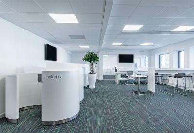 Bright coworking space with curved white privacy booths and a small indoor tree.
