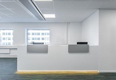 Clean, minimalist white reception desk in a brightly lit lobby area.