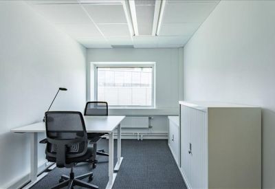 Bright two-person office suite with white desks and black mesh chairs.