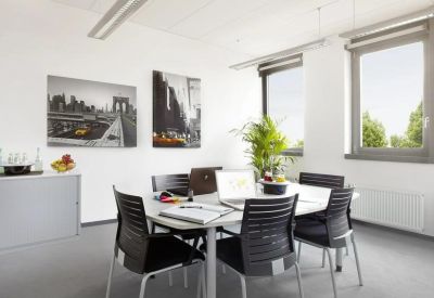 Sunlit private office with a white table, black chairs, and city skyline artwork.