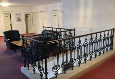 Communal lounge area featuring black leather armchairs and a decorative wrought-iron railing.