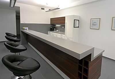 Contemporary breakroom kitchen with long dark wood breakfast bar and modern stools.