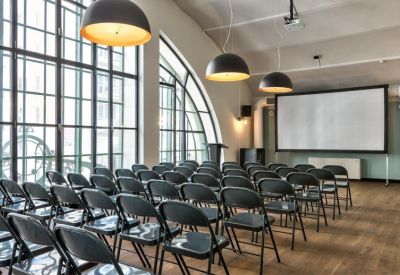 Auditorium style meeting room with rows of black chairs and a large presentation screen.