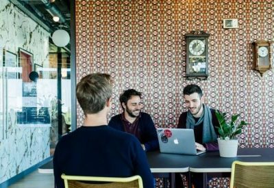 Coworking space featuring a patterned feature wall and people at a long desk.