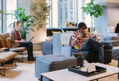 Spacious communal lounge at Kurfürstendamm 11 with sofas, plants, and natural light.