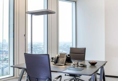 Modern private office suite with a dark desk, ergonomic chairs, and floor-to-ceiling windows.