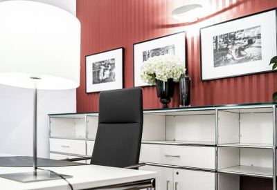 Modern private office with a red accent wall and minimalist white shelving.