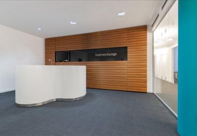 Modern curved white reception desk against a warm wood-paneled wall.