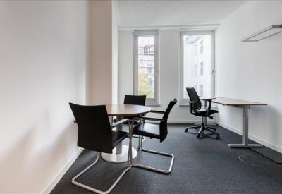 Private office featuring a round meeting table and a separate workstation by the window.