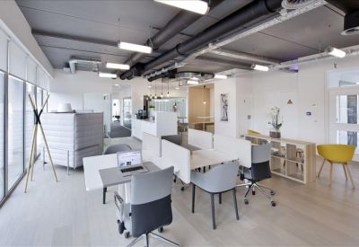 Modern coworking space with exposed ceilings and wooden floors.