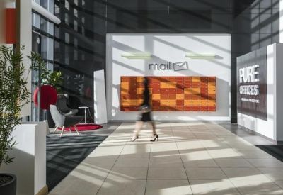Modern lobby with a central reception desk and bright floor-to-ceiling windows.