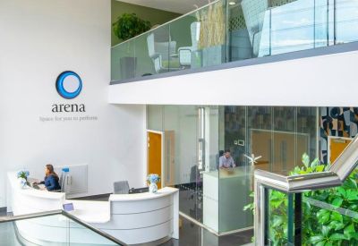 Bright double-height reception area with white curved desk and mezzanine level.