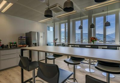 Modern communal kitchen and break area with high tables and pendant lighting.