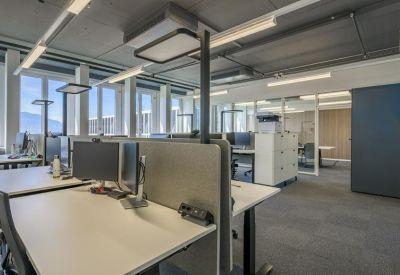 Bright open-plan office space with multiple workstations and large windows.