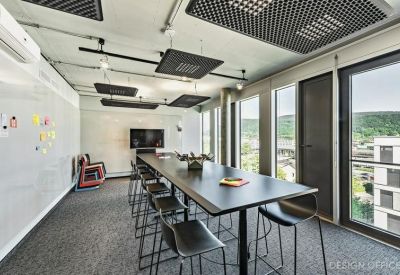 Long communal high table with stools in a bright, modern coworking space with mountain views.