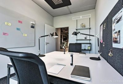 Internal two-person office suite with whiteboard and adjustable desk lamps.