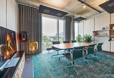 Sophisticated meeting room with a teal rug, wooden table, and digital fireplace display.