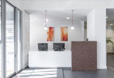 Reception desk with white counters, wood accents, and modern pendant lighting.