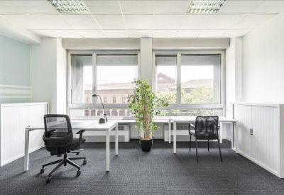 Bright private office suite with white desks and a potted plant.