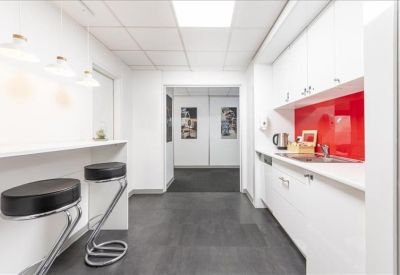 Modern communal kitchen and break area with white cabinetry and a vibrant red backsplash.