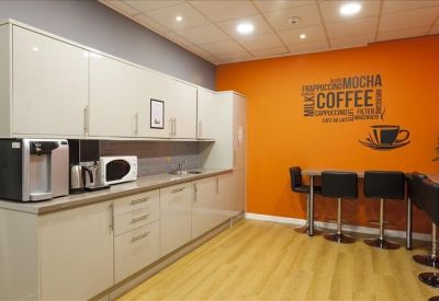 Communal kitchen and breakout area with a vibrant orange wall and coffee-themed graphics.