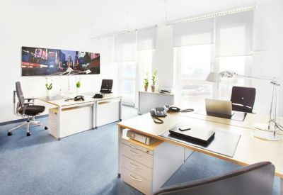 Spacious two-person open-plan office with white desks and large windows for natural light.