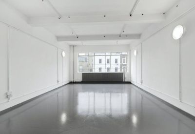 Spacious empty studio with polished grey floors and white walls reflecting natural light.