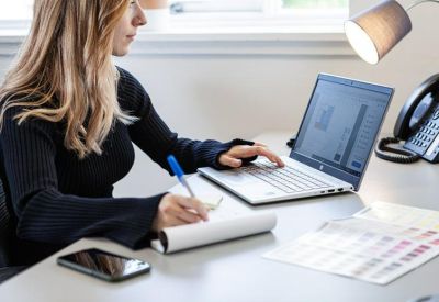 Person working on a laptop at a bright office desk.