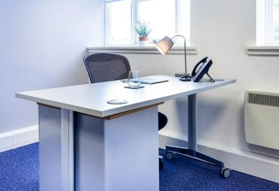 Modern private office suite with a white desk and ergonomic chair.