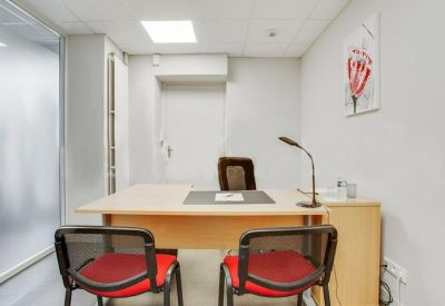 Private office suite with a wooden desk and two red guest chairs.