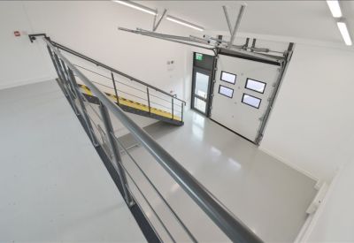 Spacious white-walled industrial unit with a mezzanine level and overhead loading door.