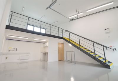 Bright, empty open-plan office space featuring a black metal staircase and mezzanine floor.