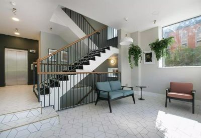 Modern reception lobby with a staircase, comfortable seating, and hanging green plants.