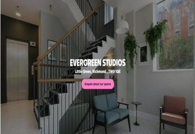 Modern lobby with a staircase, grey seating area, and potted hanging plants.