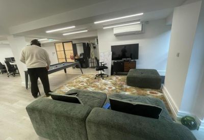 Breakout area featuring a pool table, green velvet sofas, and a large television.