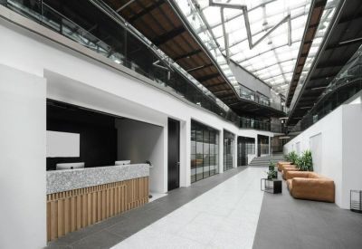 Reception area with a wooden slat desk and marble top under a glass atrium ceiling.