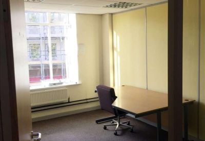 Private office suite featuring a wooden desk, purple task chair, and large window.