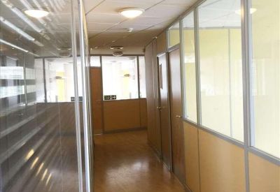 Narrow office corridor with glass partitions and wooden flooring.