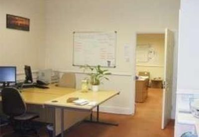 Functional two-desk private office suite with a whiteboard and green plant.