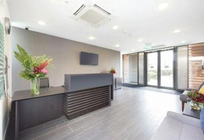Bright reception area featuring a modern dark wood desk and a large floral arrangement.