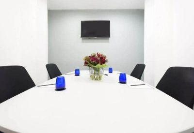 Minimalist meeting room with a large white conference table and blue glassware.