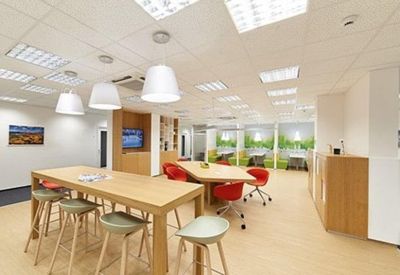 Bright meeting area with warm wood accents, pendant lighting, and colorful red chairs.