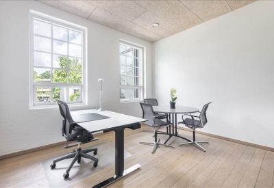 Bright private office with two windows and a small round meeting table.
