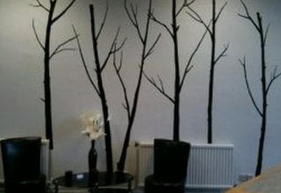 Modern breakout area with decorative tree branch wall art and black leather armchairs.