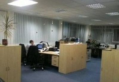 Spacious open-plan office with multiple desks, computer monitors, and a potted plant.