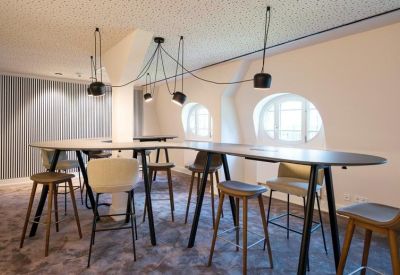 Co-working space with high tables, stools, and arched windows.